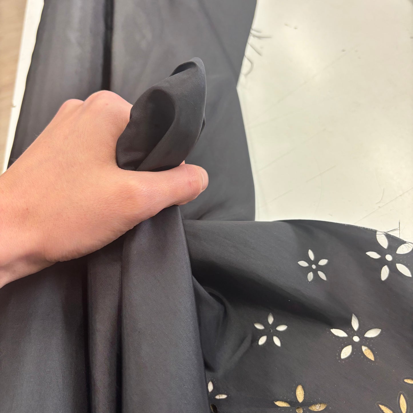 Presenting a Hand holding Blowout black fabric with a subtle pattern against a neutral background