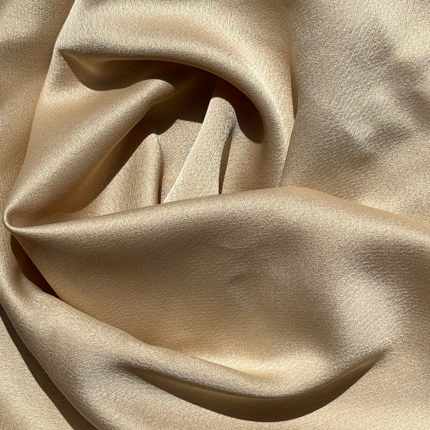 celebrity displaying the gold colored version of a polyester microfiber double sided matte face & satin back crepe with fluid drape