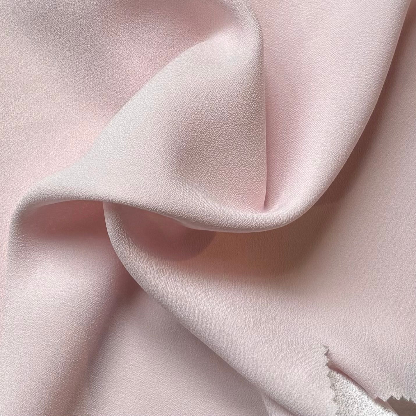 celebrity displaying the pale pink colored version of a polyester microfiber featuring a double sided matte face & satin back crepe with fluid drape