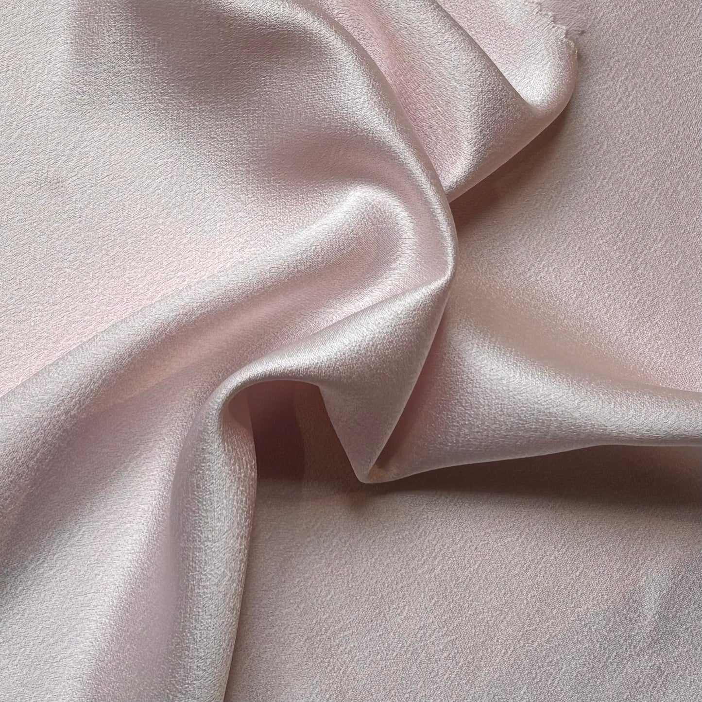 celebrity displaying the pale pink colored version of a polyester microfiber featuring a double sided matte face & satin back crepe with fluid drape