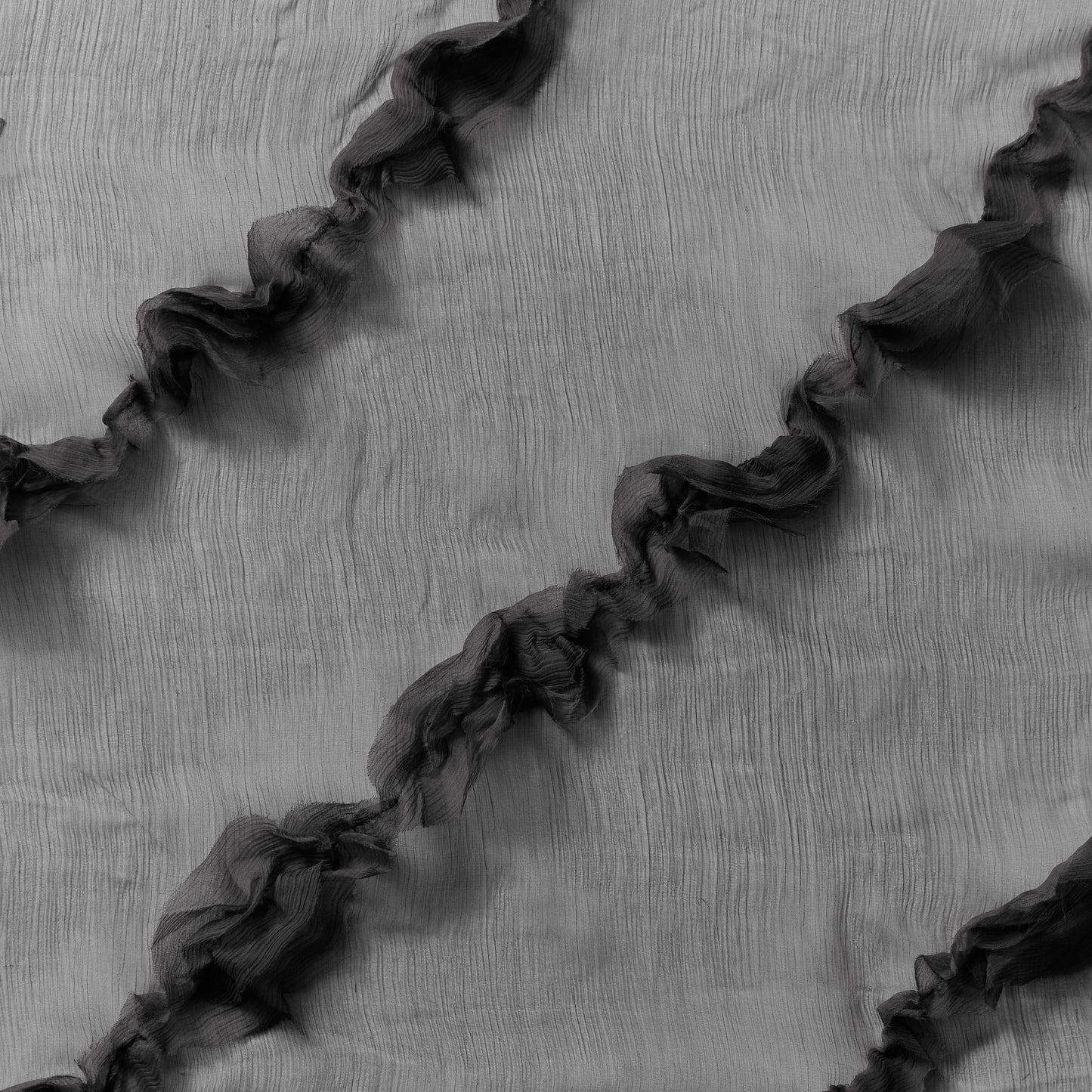 Displaying presenting black colored crinkle light weight sheer pure silk chiffon with diagonal ruffle flounce
