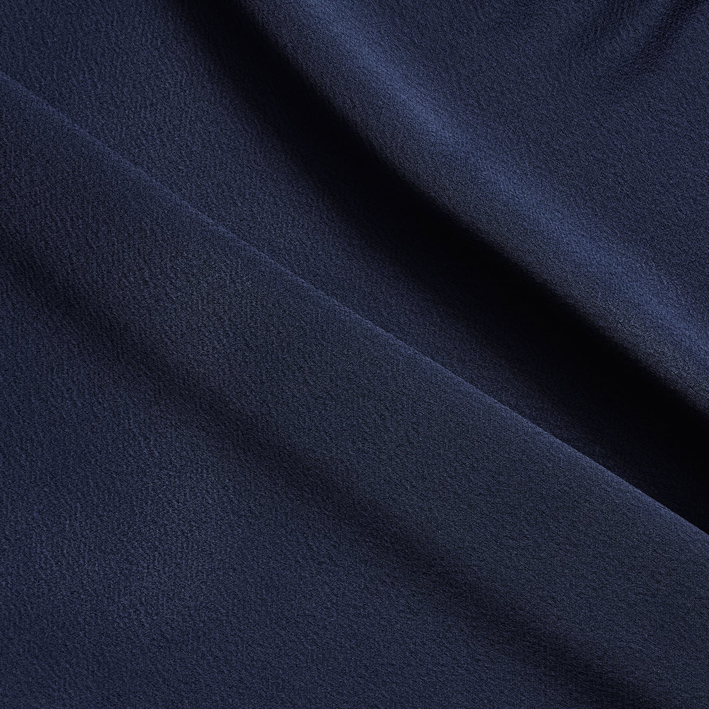 celebrity displaying the dark navy colored version of a polyester microfiber satin back crepe with fluid drape
