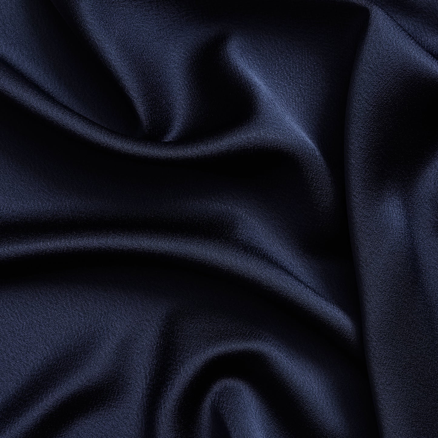 celebrity displaying the dark navy colored version of a polyester microfiber satin back crepe with fluid drape