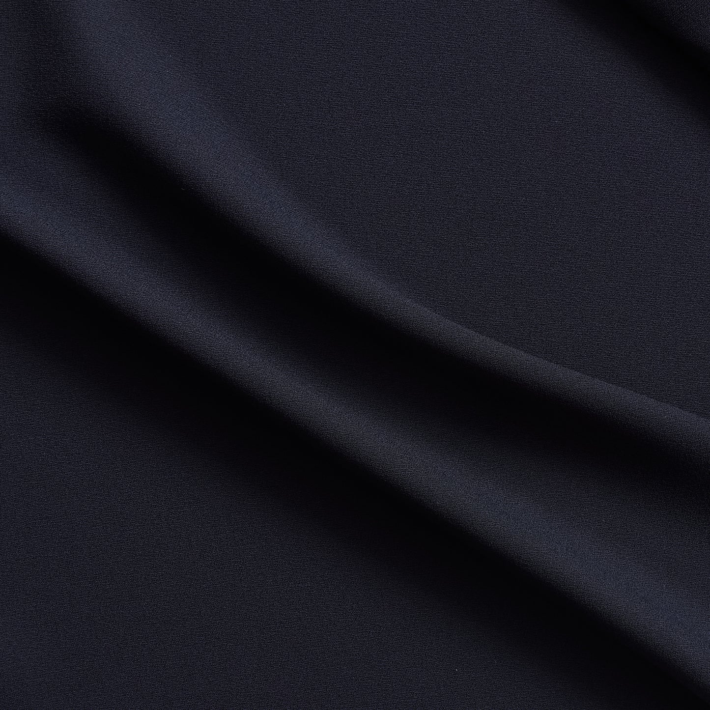 celebrity displaying the dark navy colored version of a polyester microfiber satin back crepe with fluid drape