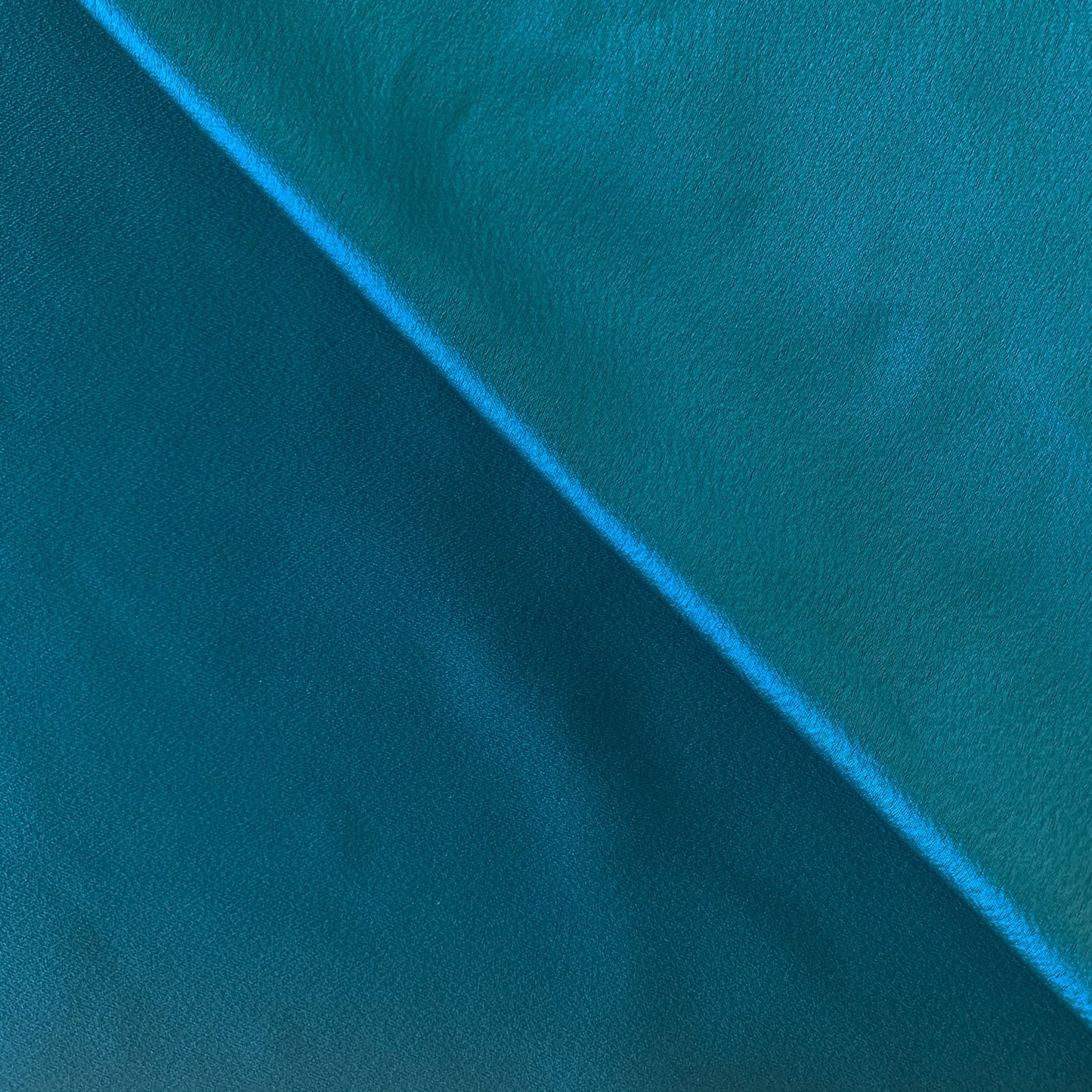 celebrity displaying the teal colored version of a polyester microfiber showing both sides with fluid drape