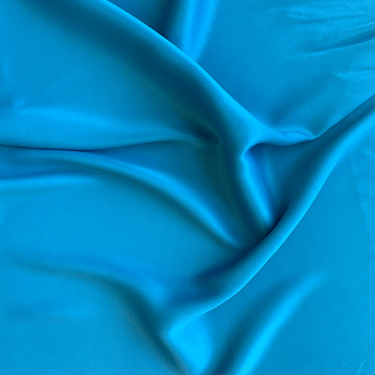 sakura presenting the blue color version of a satin bamboo and viscose blend with both satin and matte faces featuring fluid drape