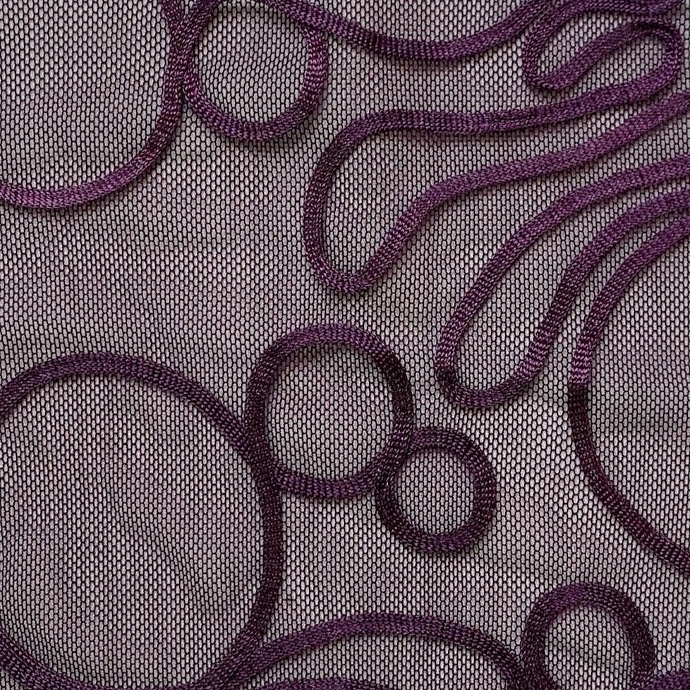 roulette presenting exhibiting the plum color version of a polyester and rayon abstract circular Embroidery on fine sheer mesh in closeup