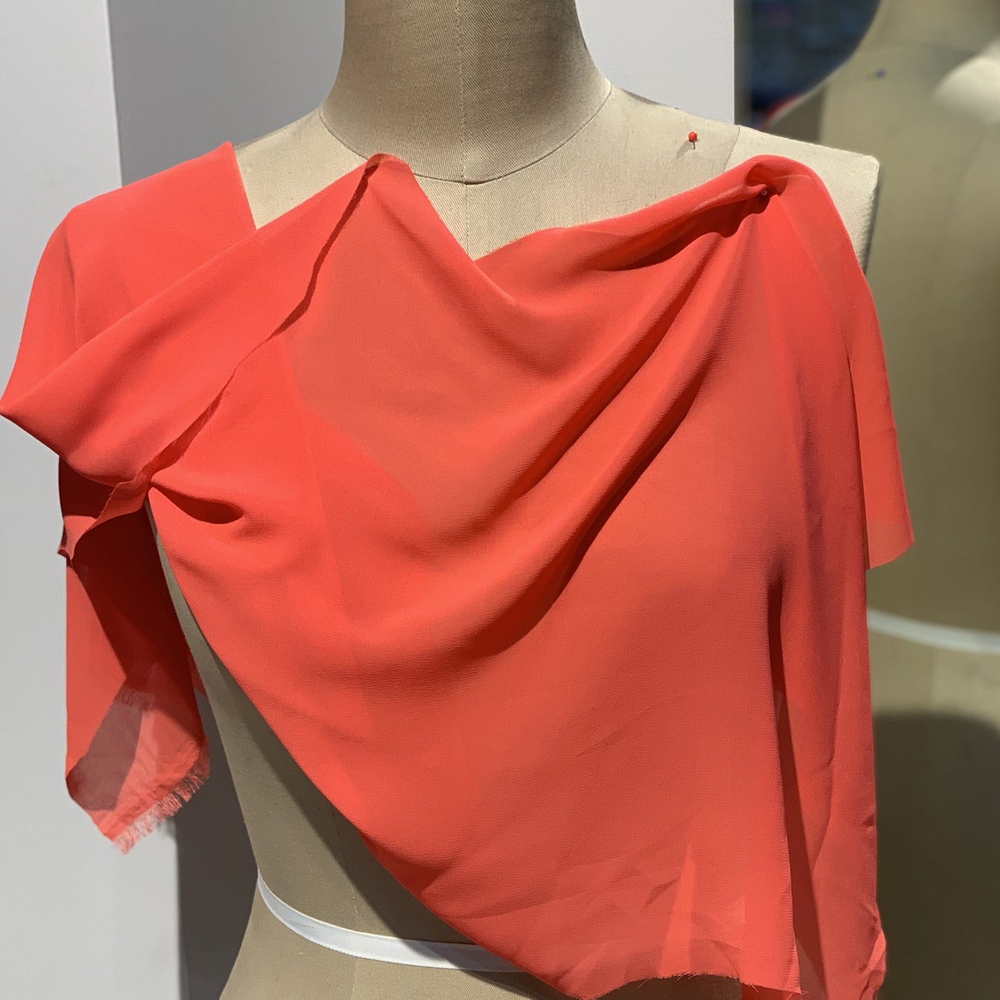 microgette presenting the coral color version of a sheer soft plain weave Polyester microfibre with matte face and good drape drapped on a mannequin