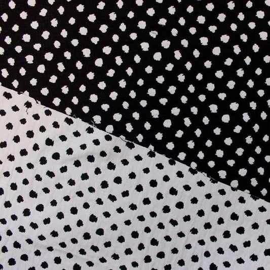 meteor presenting both sides of a stretchable, reversible, cotton poly with spandex blend featuring a dobby weave with spotty blotches showing both sides of white on black and black on white