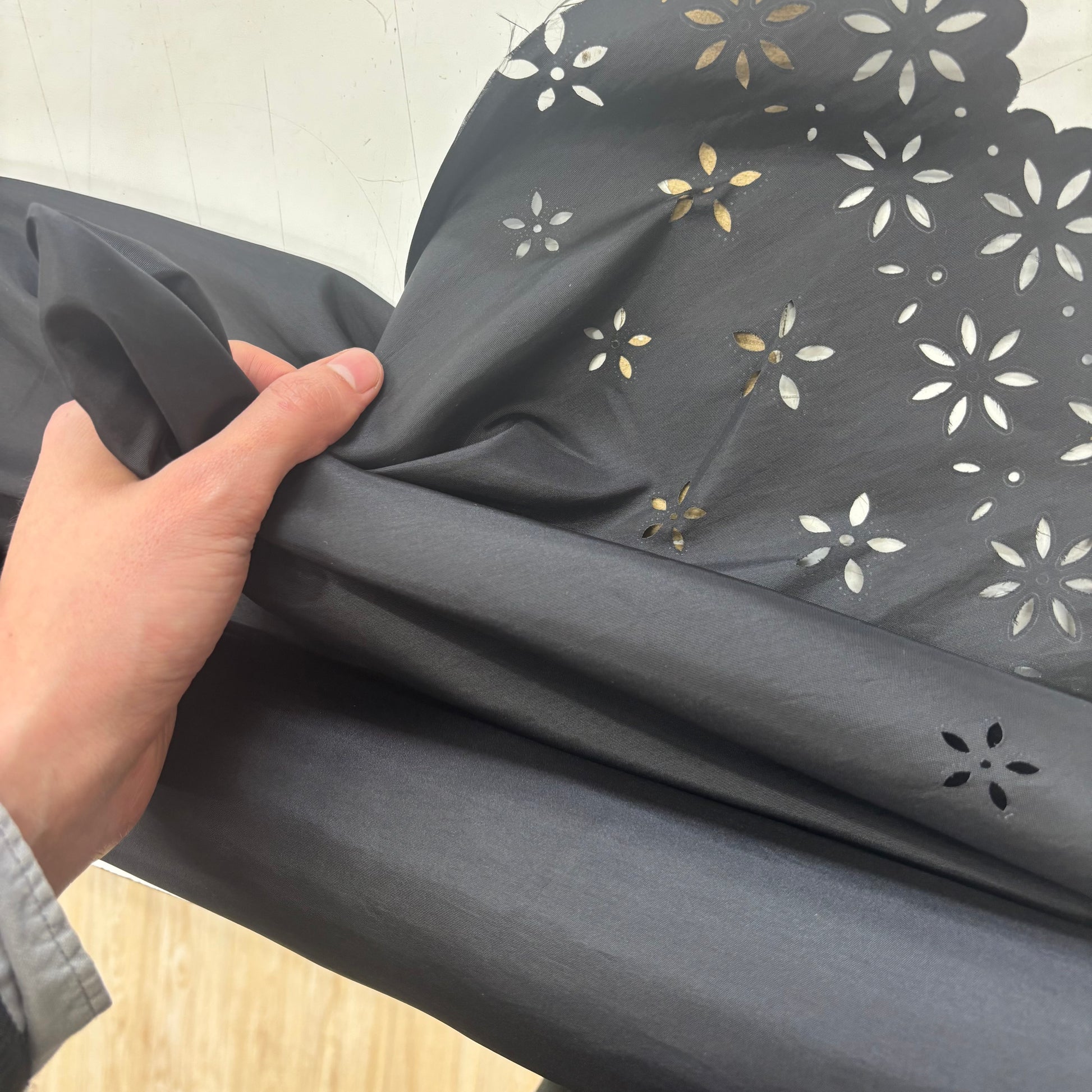 Showing the Blowout Black fabric with floral patterns with hand for scale