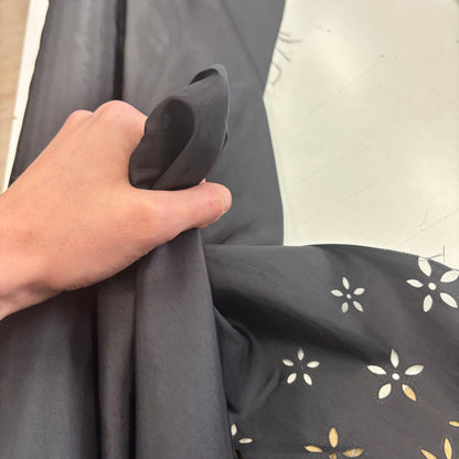 Showing a Hand holding Blowout black fabric with a subtle pattern against a neutral background