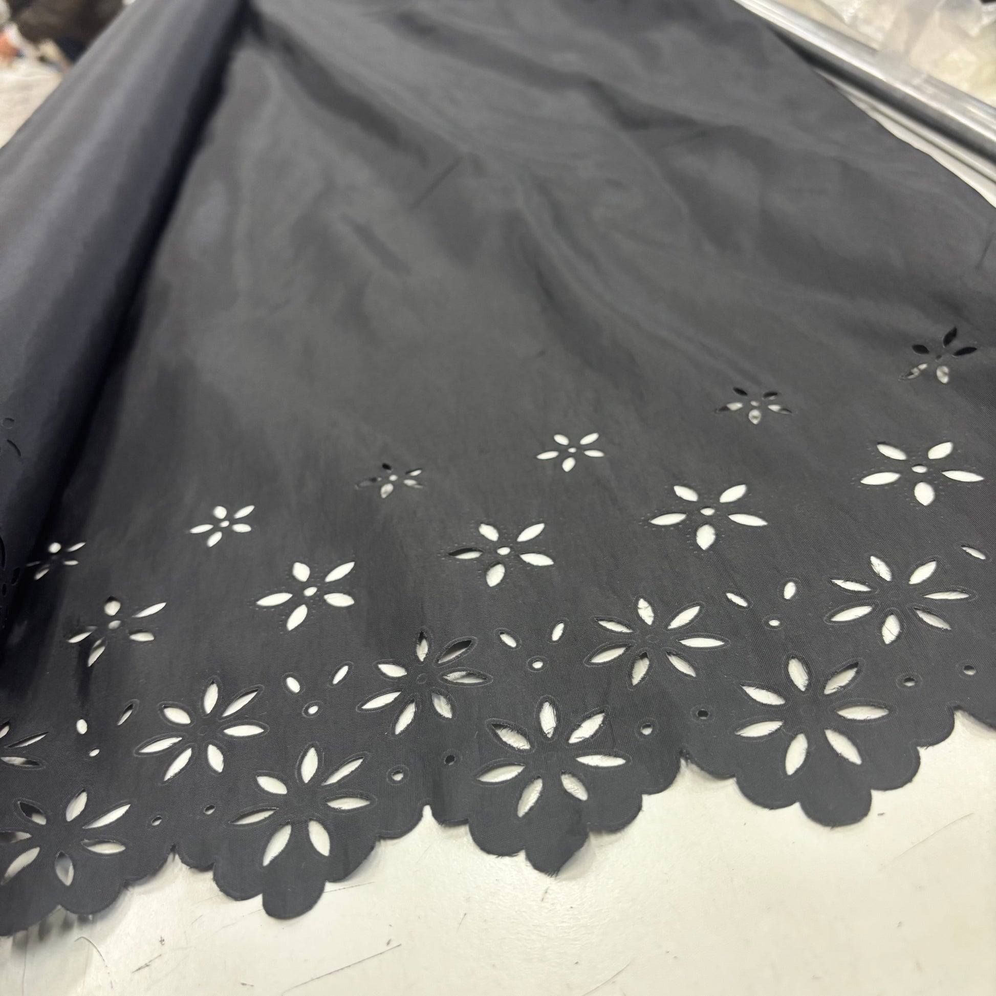 Showing Blowout Black fabric with white floral cut-out patterns on a white floor.