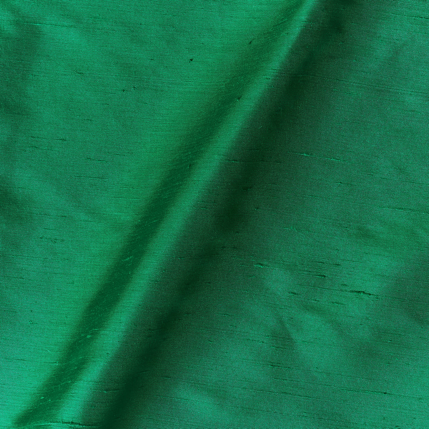 Showing Bohai Dupion pure silk in an emerald shade with moderate drape