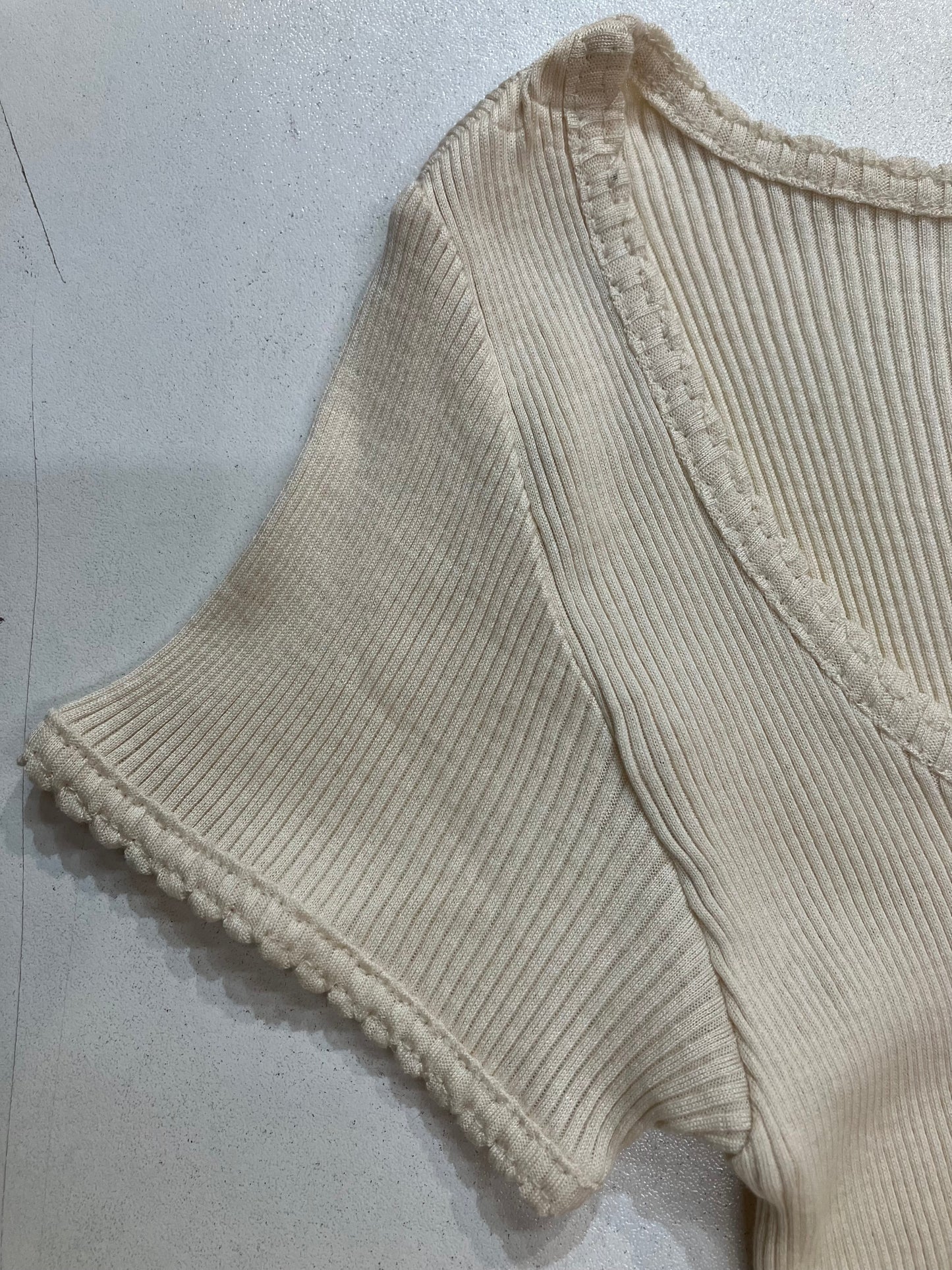 Presenting a closeup of a ecru colored silk and cotton cotton rib knit top cap sleeve