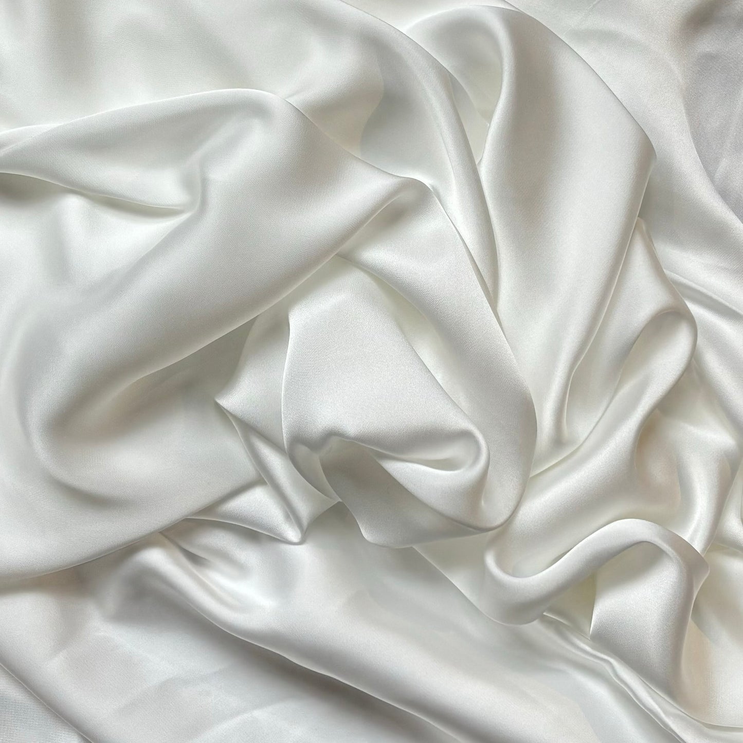 Deluxe displaying the ivory color version of a satin colored chiffon silk like pure polyester with fluid drape