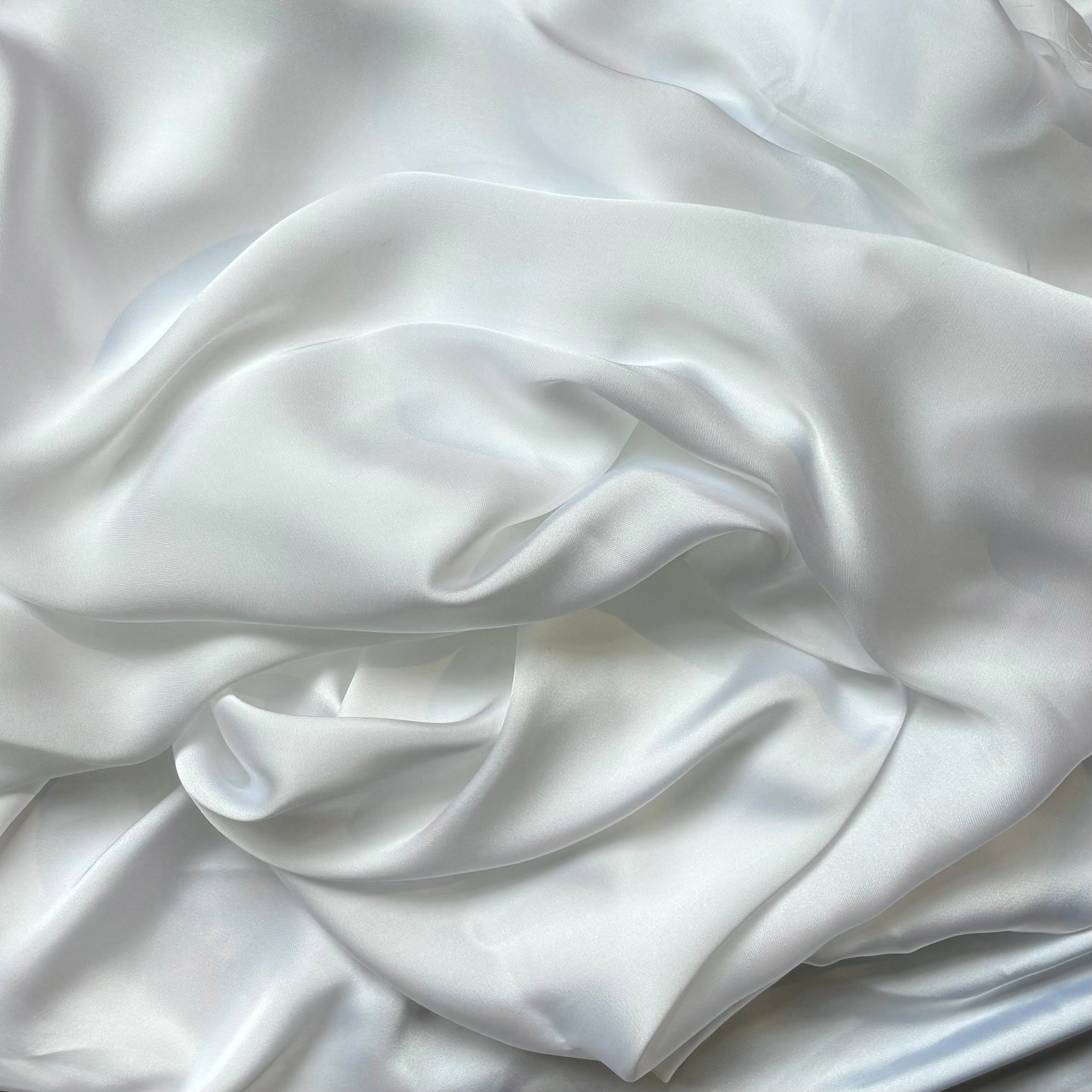 Deluxe dsiplaying the white color version of a satin colored chiffon silk like pure polyester with fluid drape