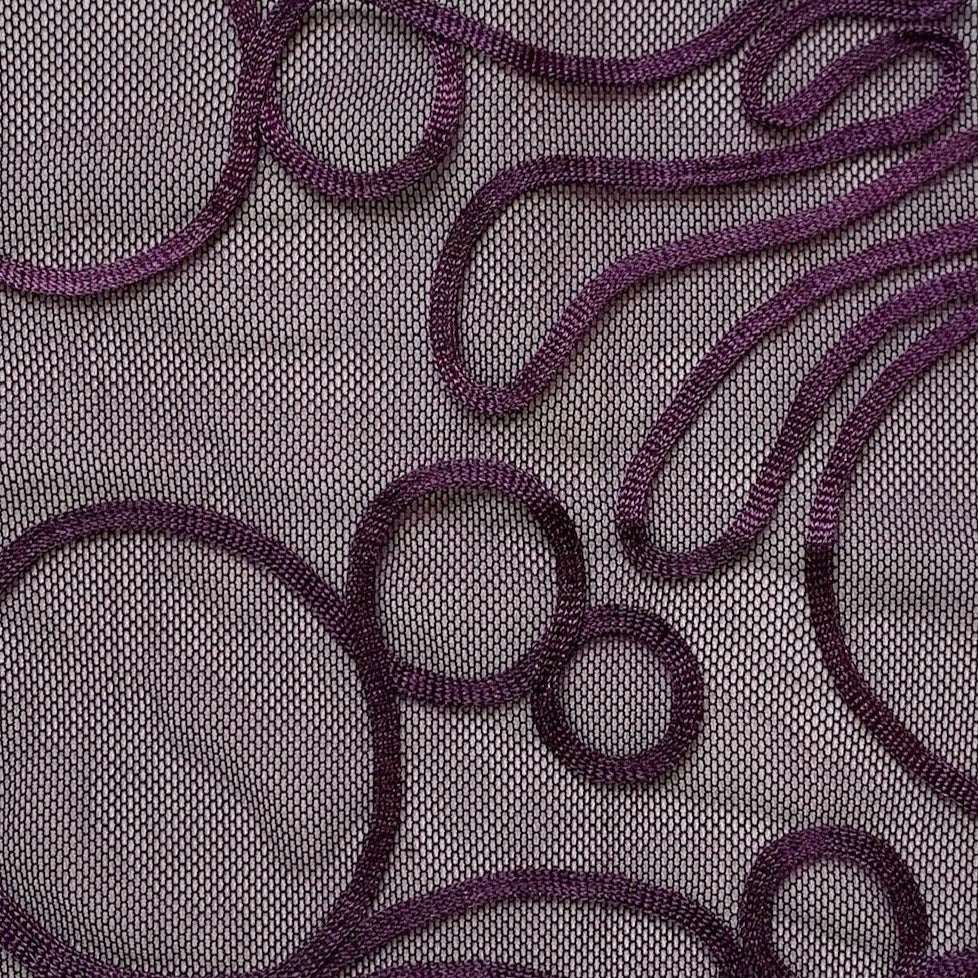 roulette showing exhibiting the plum color version of a polyester and rayon abstract circular Embroidery on fine sheer mesh in closeup