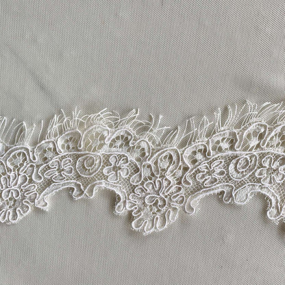 Presenting ingrid an ivory colored Scalloped rayon and nylon lace with corded embroidery and eyelash on trim in closeup