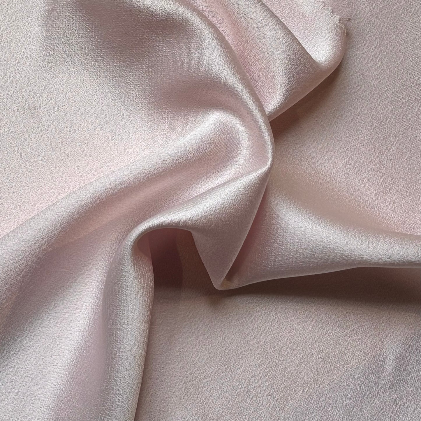 celebrity showing the pale pink colored version of a polyester microfiber featuring a double sided matte face & satin back crepe with fluid drape