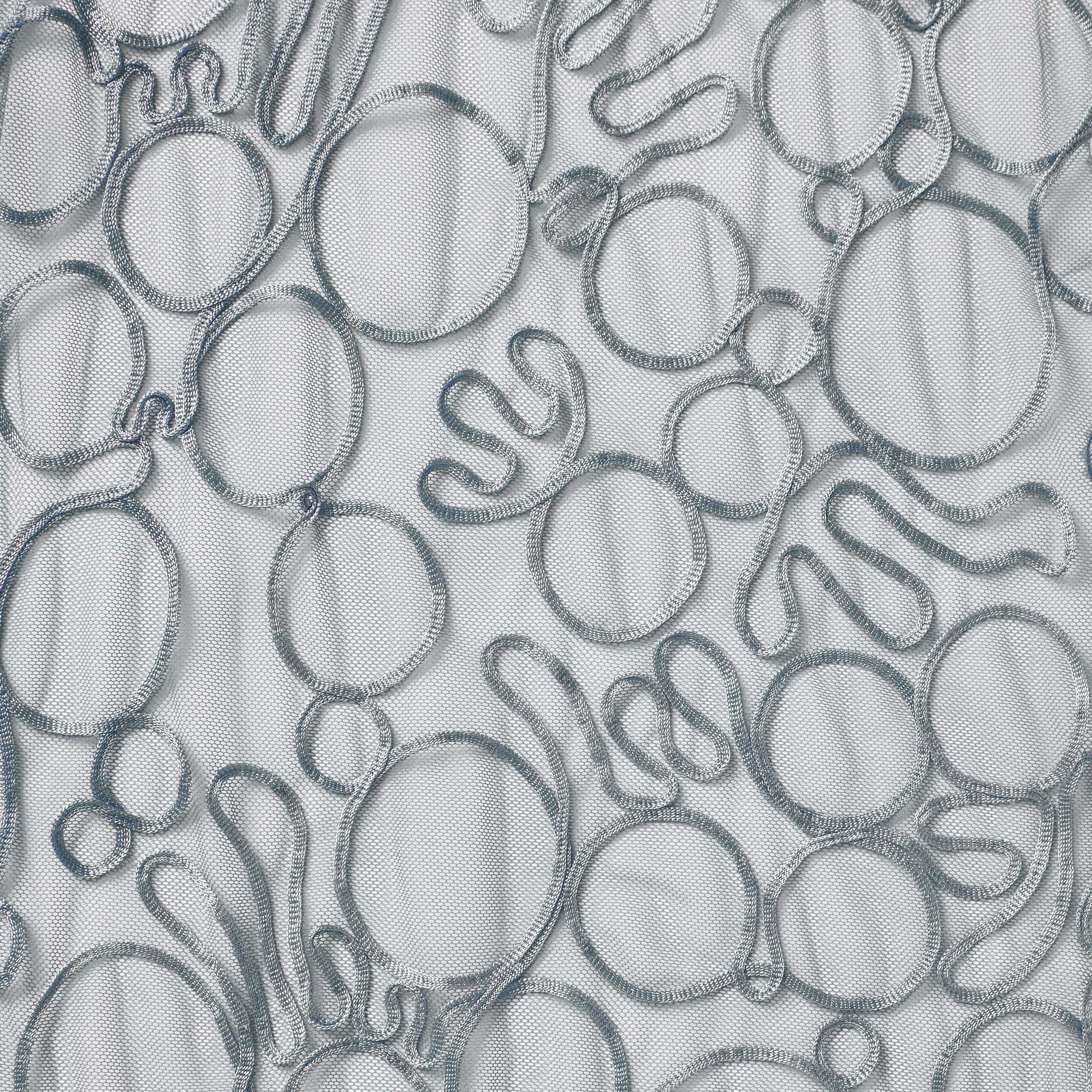 roulette showing the silver color version of a polyester and rayon abstract circular Embroidery on fine sheer mesh