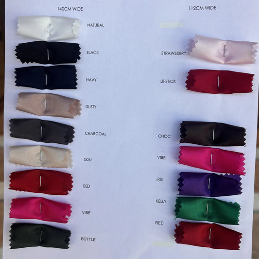 A fabric color swatch chart showing multiple small rectangular fabric samples in different colors, each labeled with a name or shade such as Natural, Black, Navy, Dusty, Charcoal, Skin, Red, Pink, Strawberry, Choc, Vibe, Kelly, and Bottle.