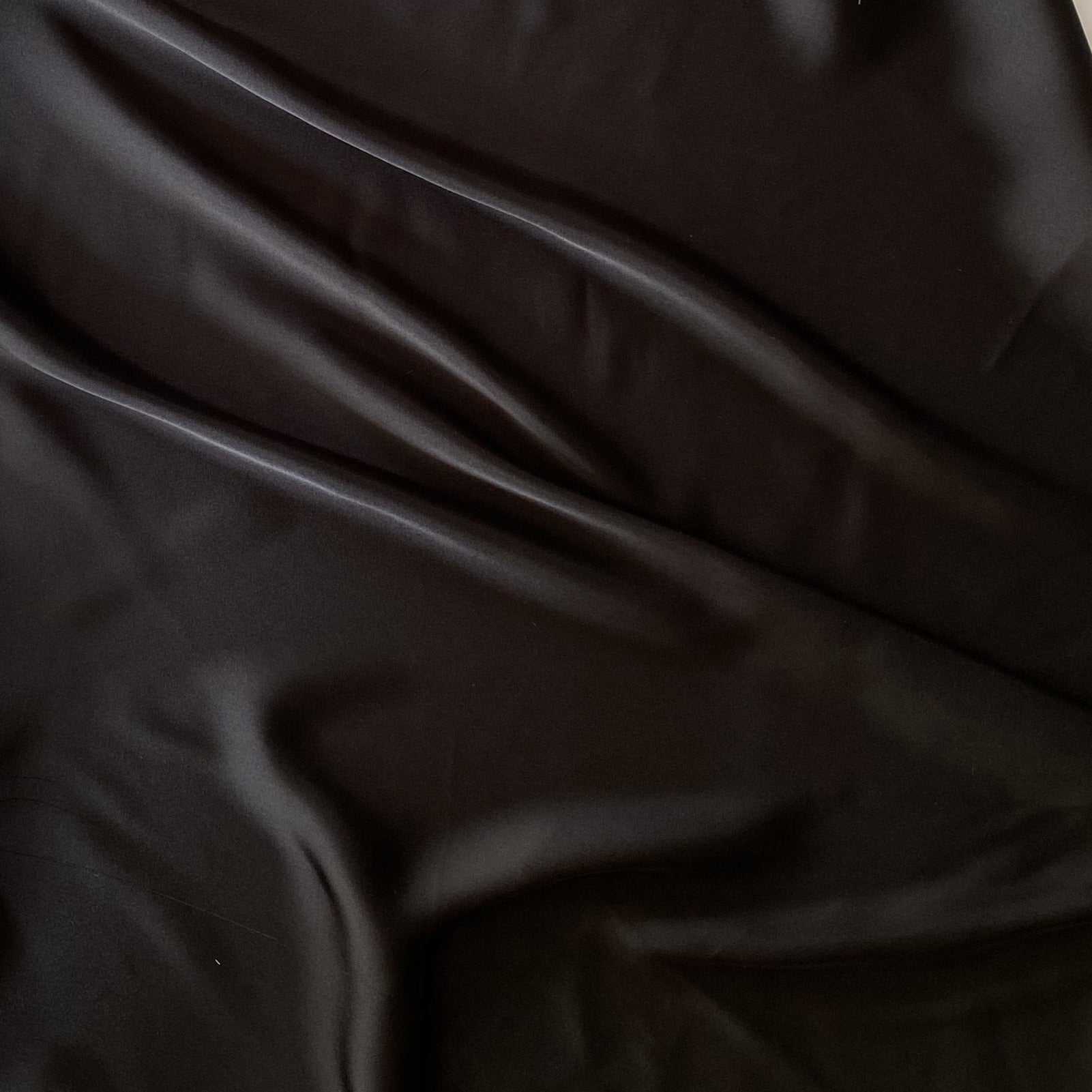 Deluxe displaying the black color version of a satin chiffon silk like pure polyester with fluid drape