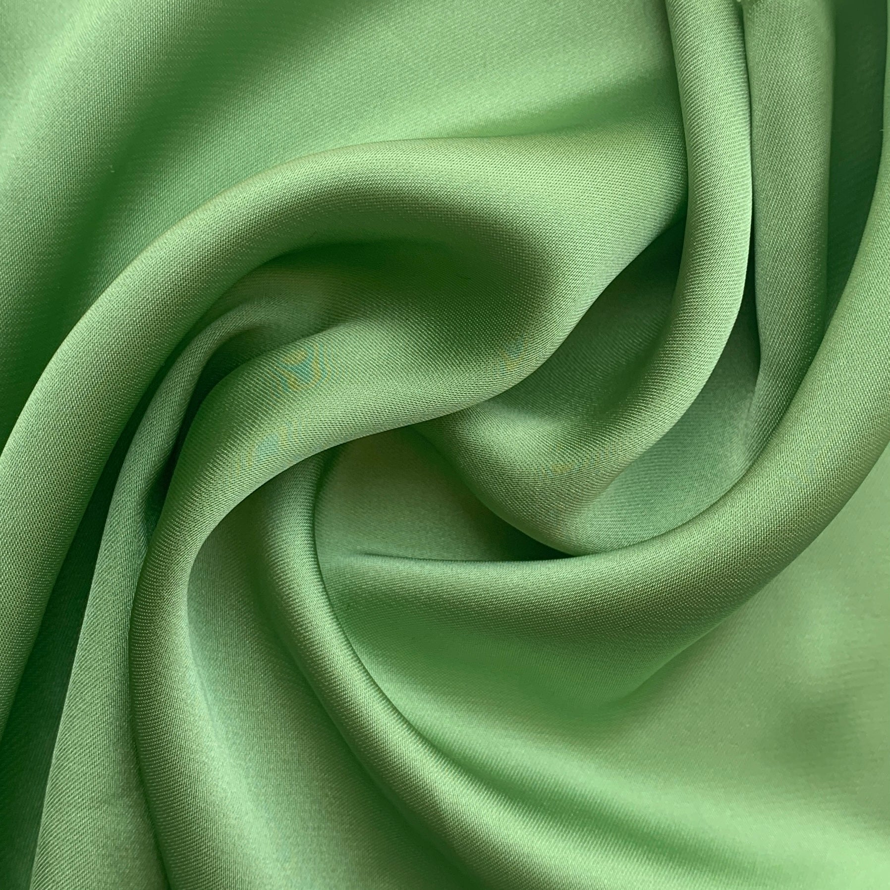 Deluxe displaying the lettuce color version of a satin chiffon silk like pure polyester with fluid drape