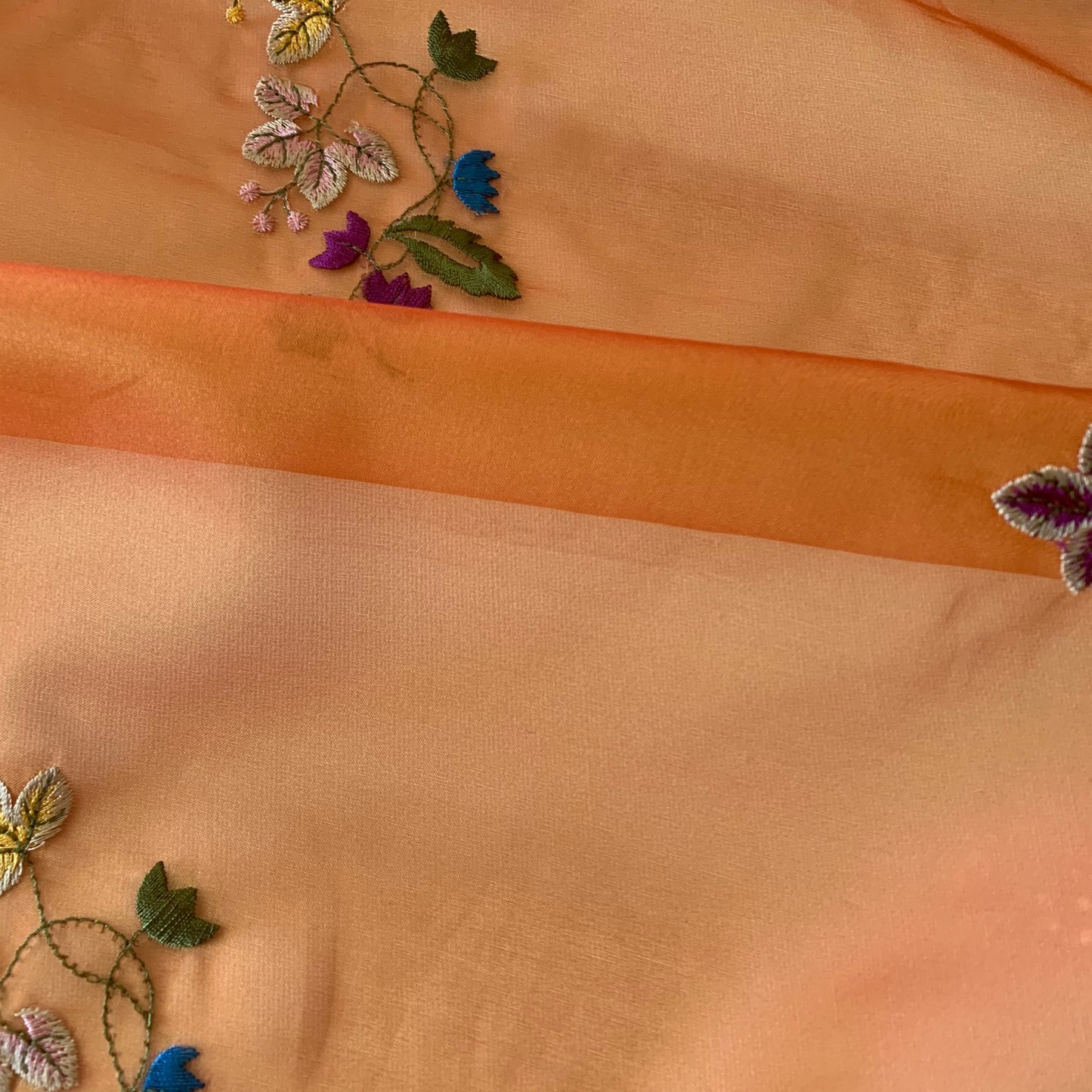 Showing venetia a saffron colored fabric with Floral rayon embroidery on silk organza